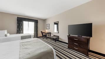 Una habitación de hotel con dos camas, un escritorio, una silla, un televisor y una cómoda.