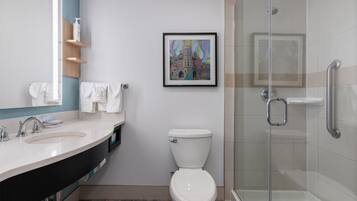 A modern bathroom with a large mirror, two sinks, a toilet, and a glass-enclosed shower.