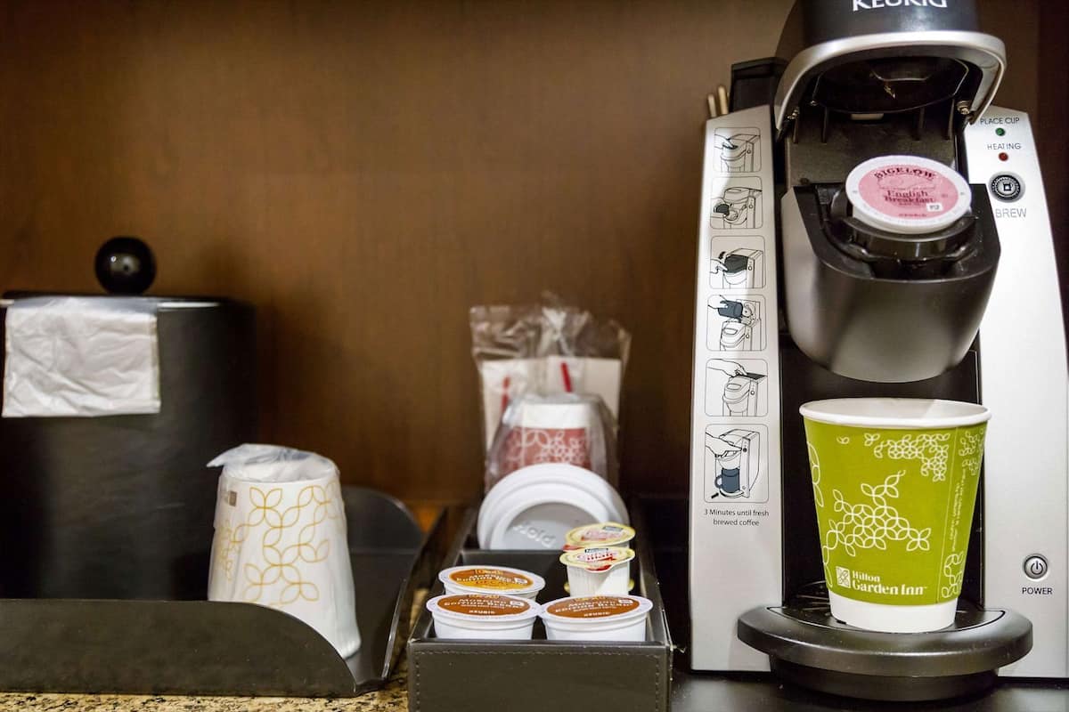 A coffee machine with a cup of coffee, disposable cups, and a tissue box.