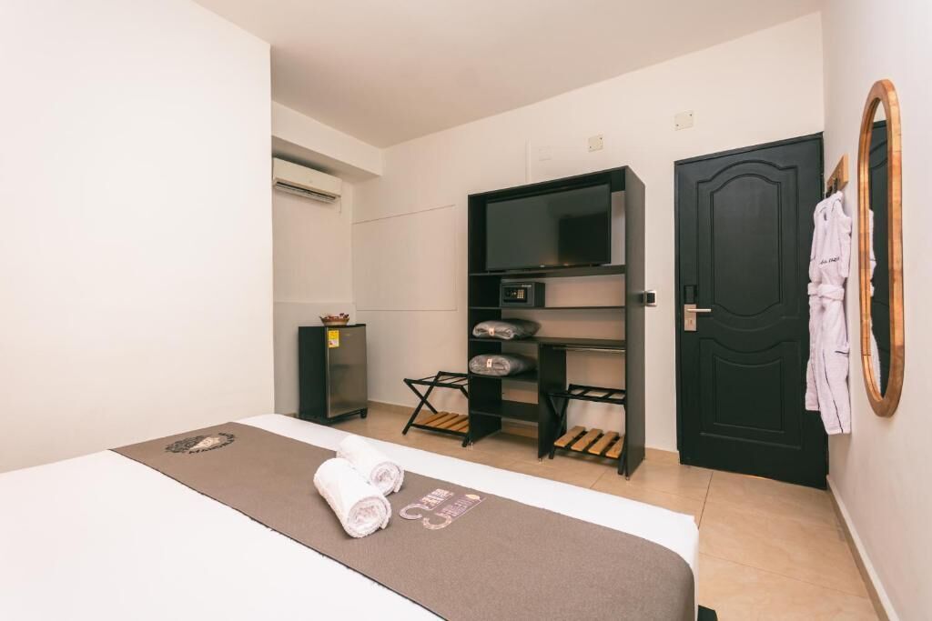 A hotel room with a bed, a TV, a wardrobe, and a door.