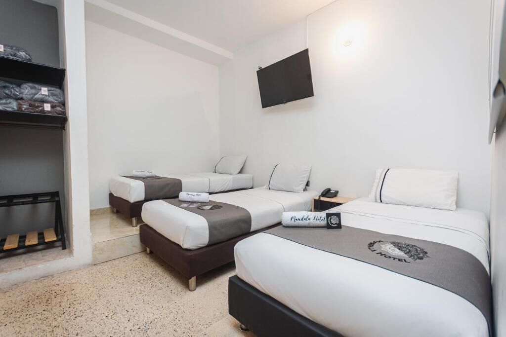 Ein Hotelzimmer mit zwei Betten, einem an der Wand montierten Fernseher und einem kleinen Schreibtisch mit Telefon.