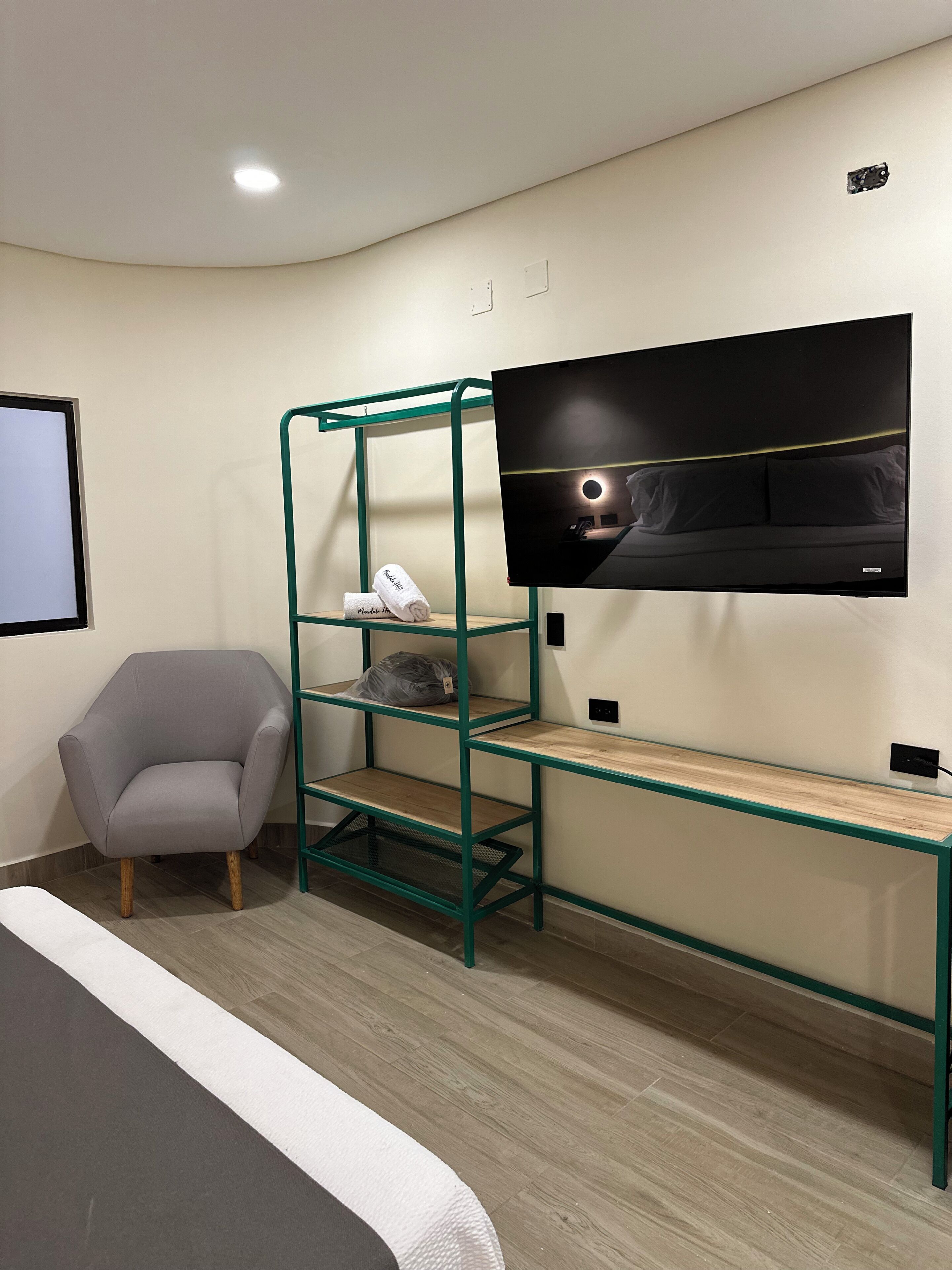 A modern hotel room with a bunk bed, a desk, a chair, and a TV mounted on the wall.