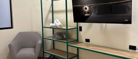 A modern hotel room with a bunk bed, a desk, a chair, and a TV mounted on the wall.