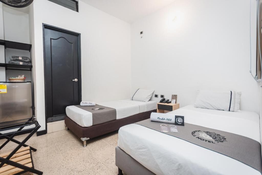Habitación de hotel con dos camas, un escritorio, una silla y un minibar.