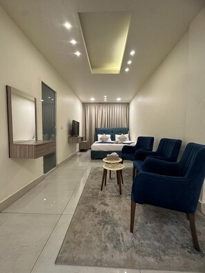 A modern hotel room with a bed, seating area, television, and a large mirror. - Orient Prince Hotel (Beirut)