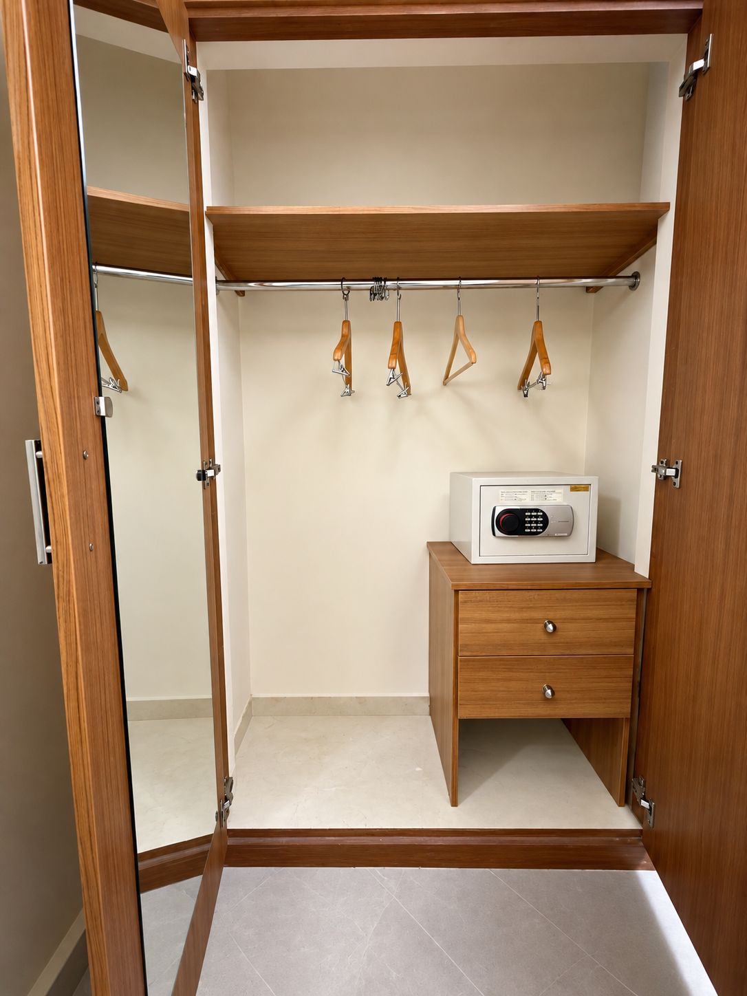 A walk-in closet with wooden shelving, a hanging rod, and a small wooden cabinet.