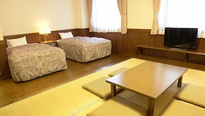 A hotel room with two beds, a wooden table, and a television on a stand. - Rakuchin Hotel (Naha)