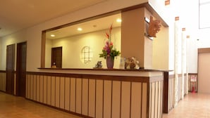 A reception desk with a vase of flowers, a wooden head sculpture, and a fire extinguisher. - Rakuchin Hotel (Naha)