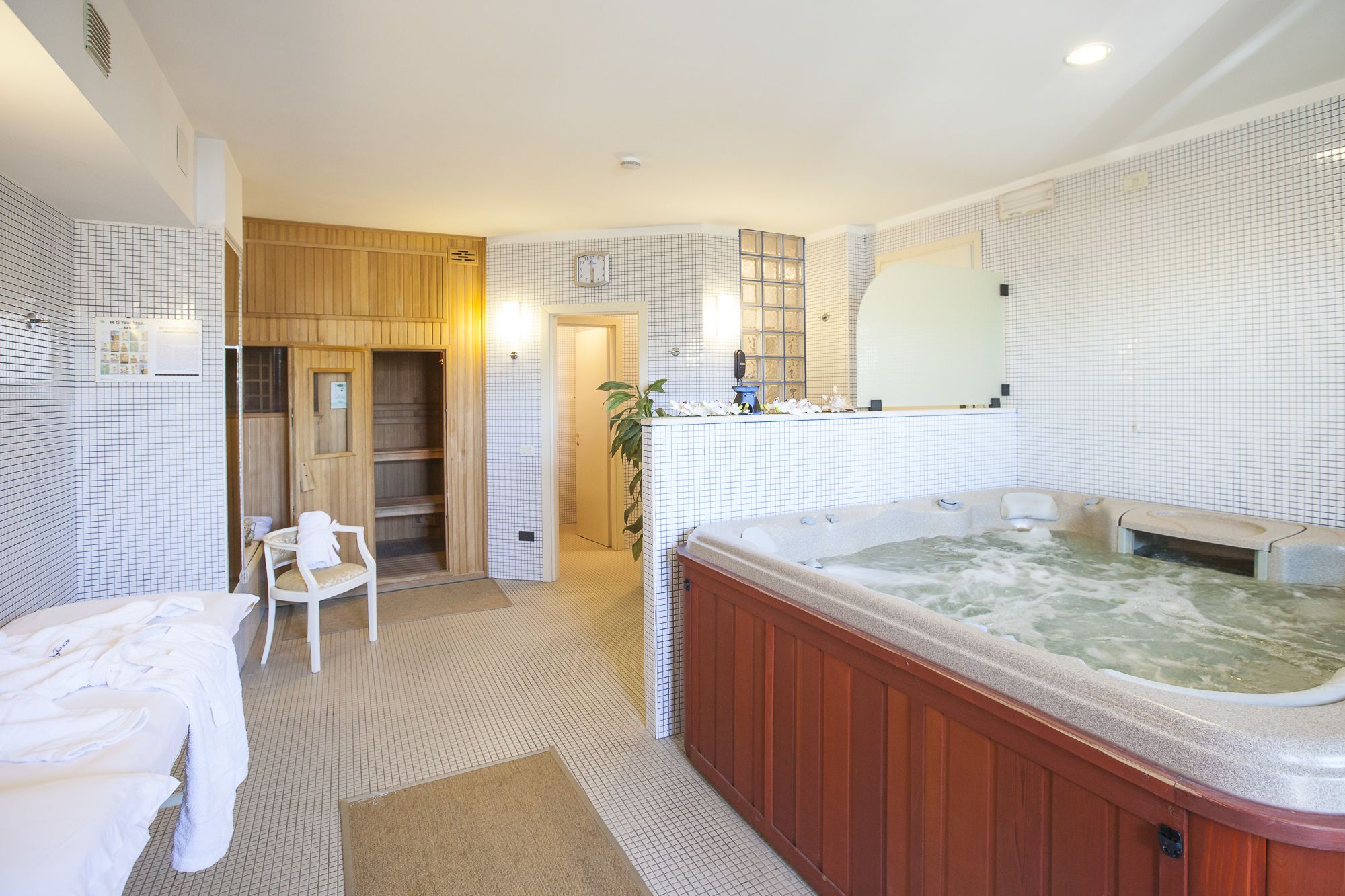 Un baño moderno con una bañera grande, una sauna de madera y una silla blanca.