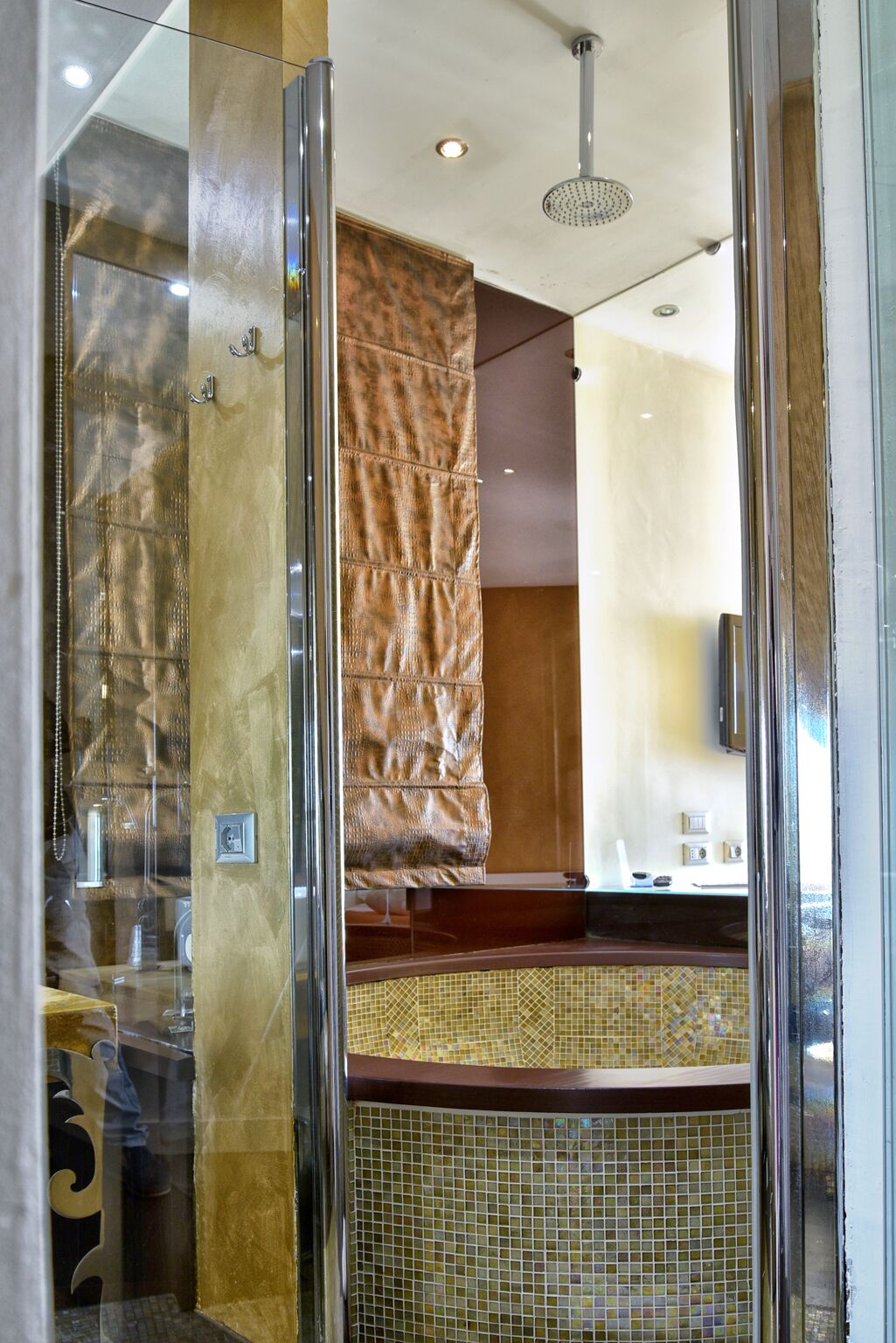 A modern bathroom with a glass shower enclosure, a patterned curtain, and a tiled floor.