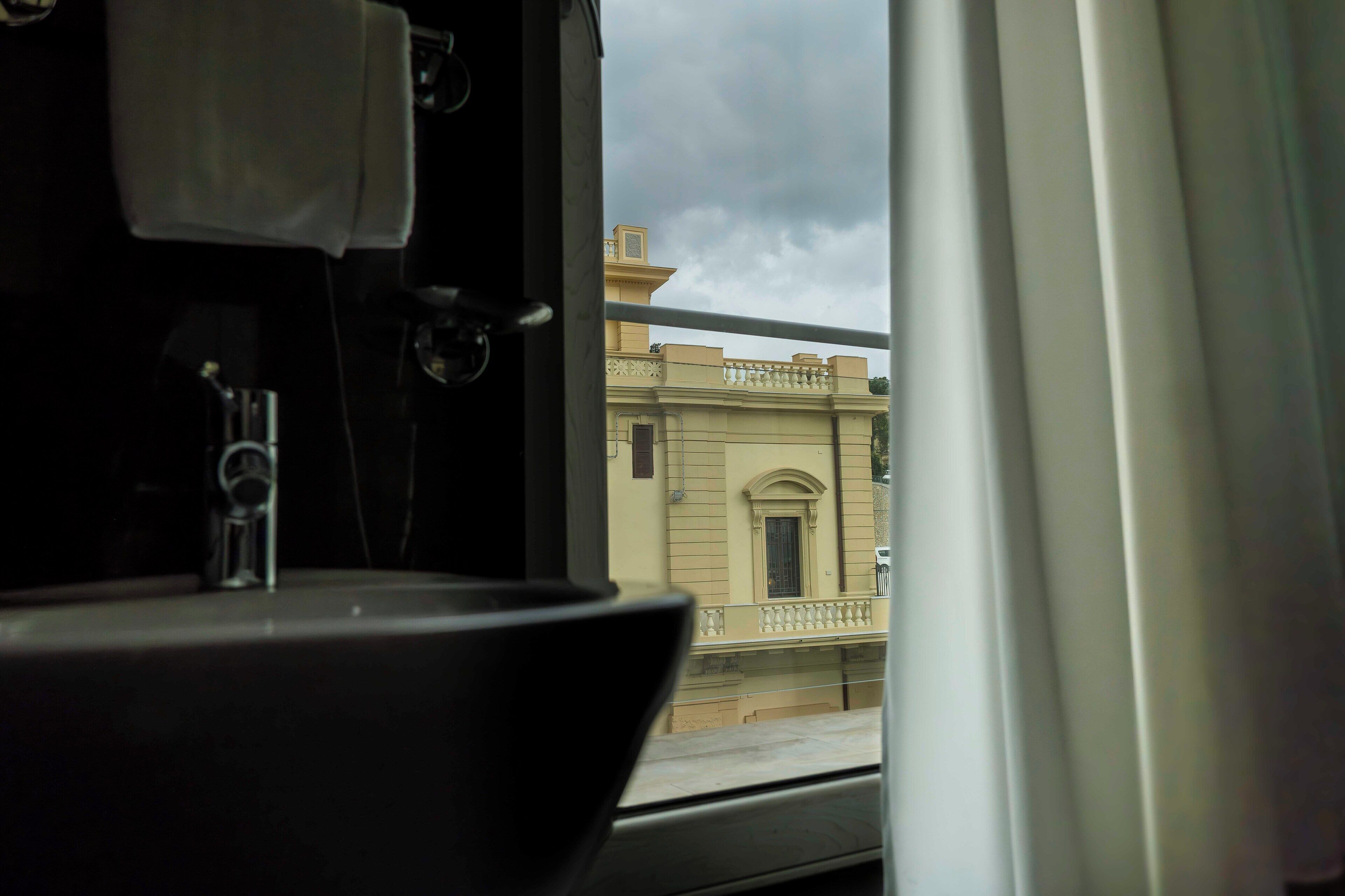 Une salle de bain avec un lavabo et une fenêtre donnant sur un immeuble.
