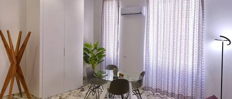 A compact living space with a dining area, a sofa, and a plant.
