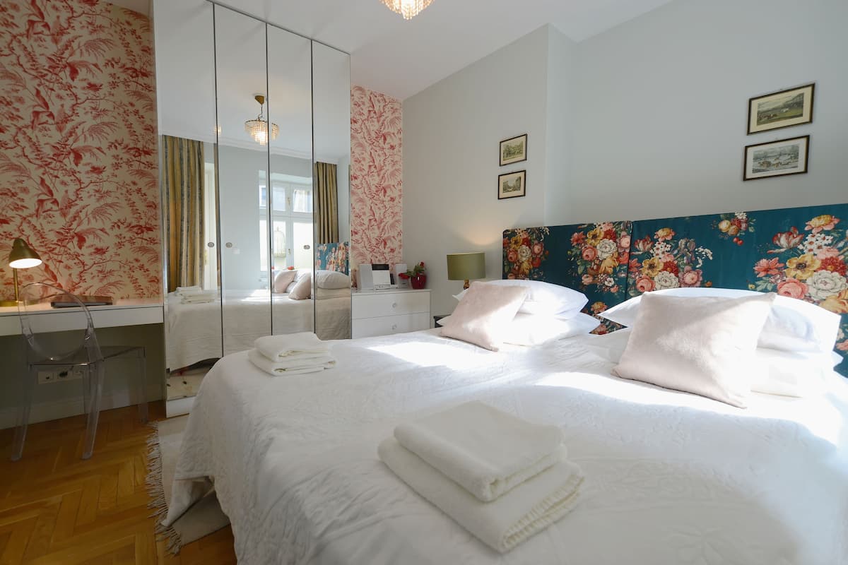 Ein Hotelzimmer mit einem großen Bett, einem Nachttisch, einem Spiegel, einem Schreibtisch und einem Sessel.