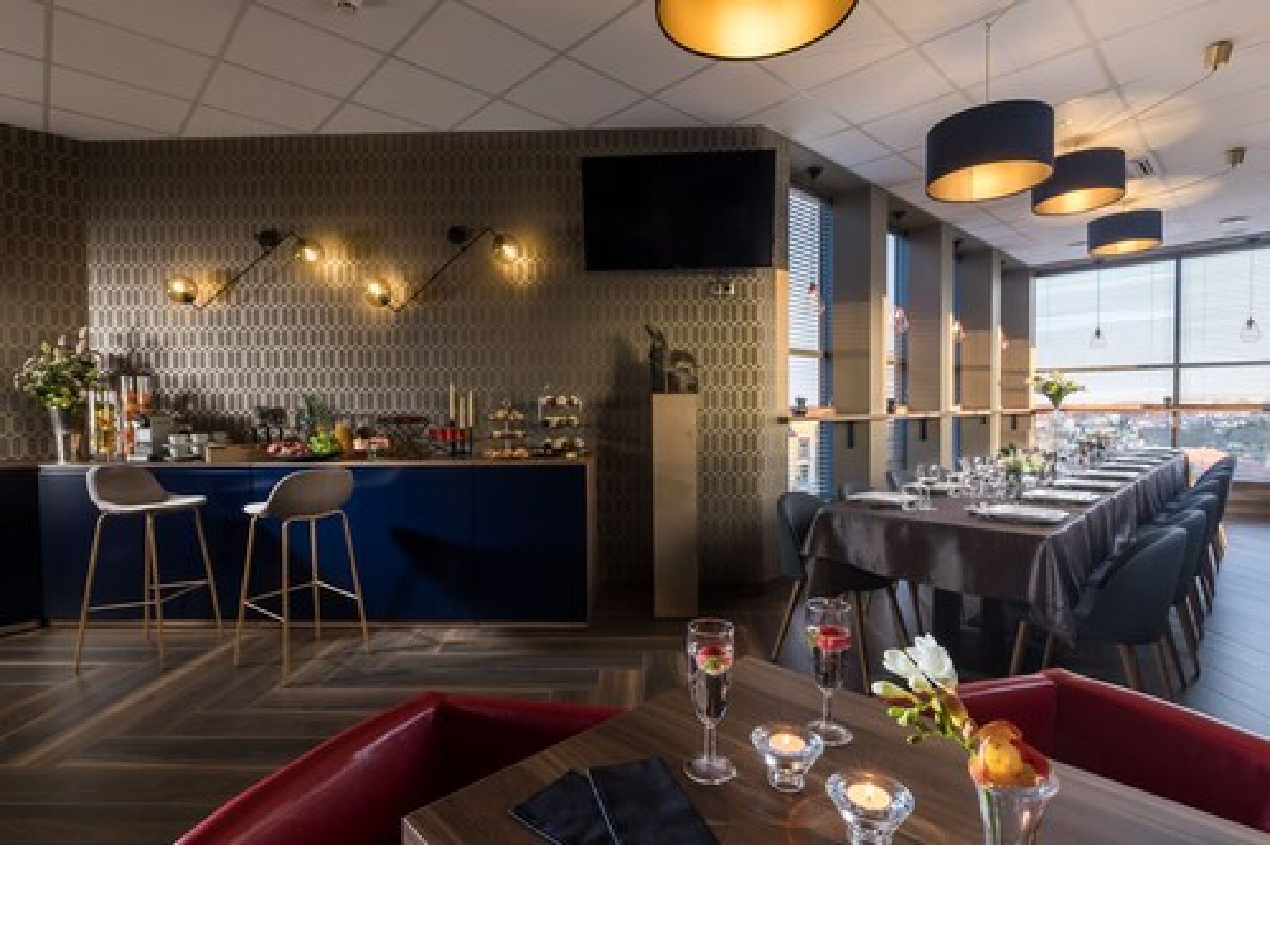 A modern restaurant with a bar area, high ceiling, and large windows.