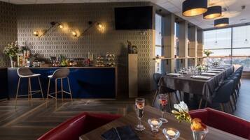 A modern restaurant with a bar area, high ceiling, and large windows.