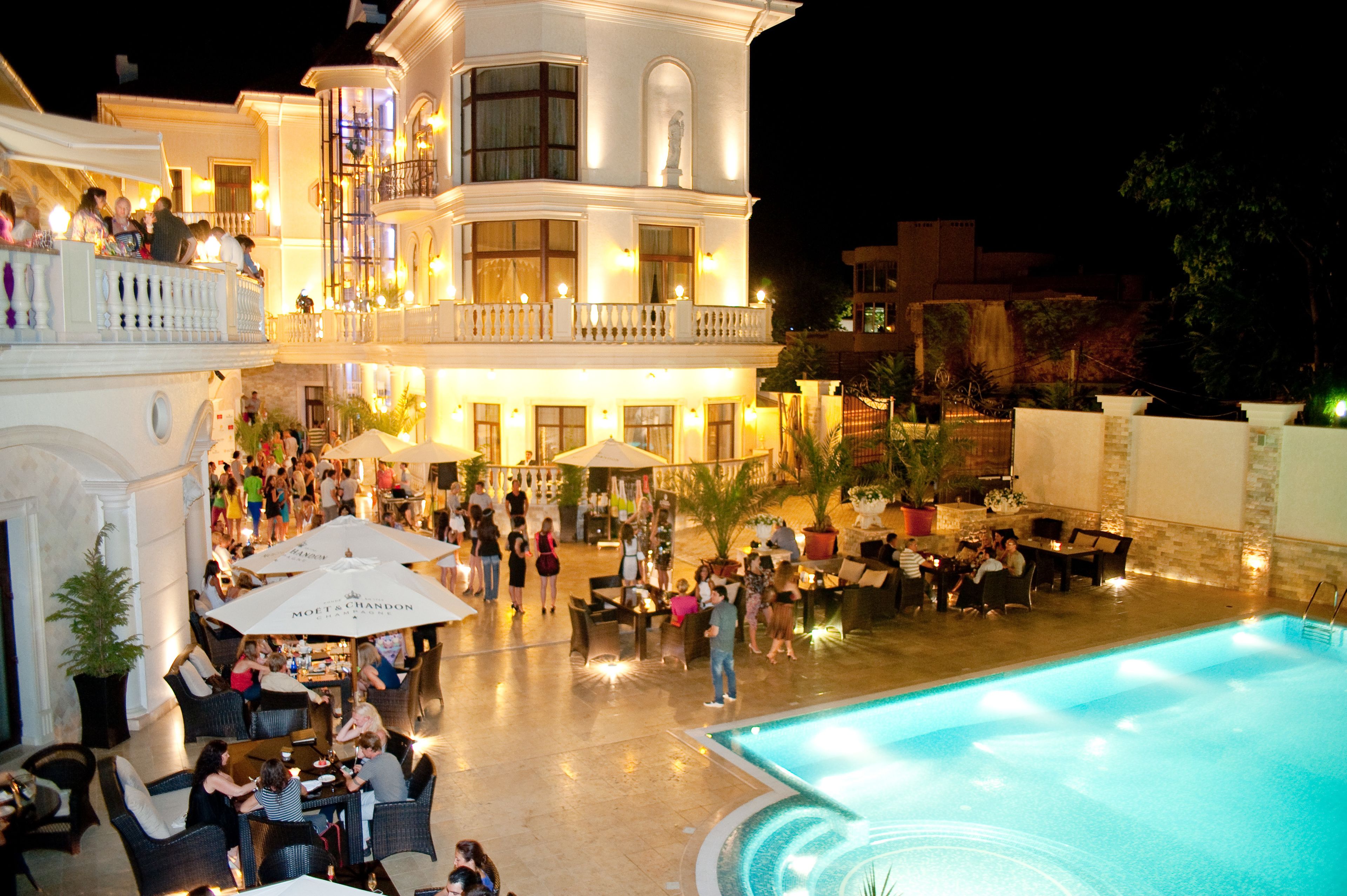 A multi-story hotel with outdoor seating and a swimming pool.
