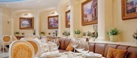 A dining area with round tables set for a meal, featuring white tablecloths and silverware.