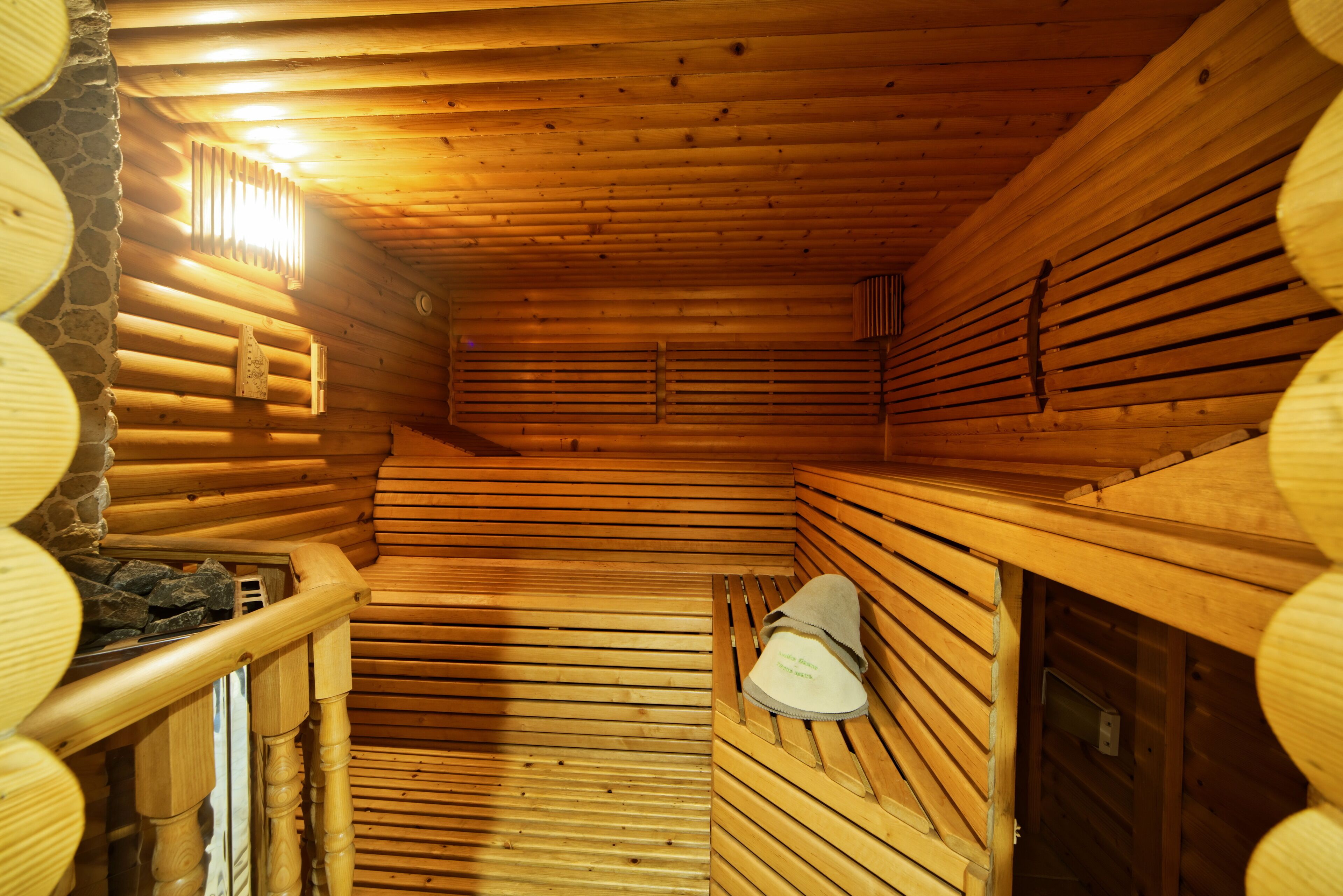 Interior de una cabaña de troncos con paredes de madera, una sección de pared de piedra y un banco con una toalla.