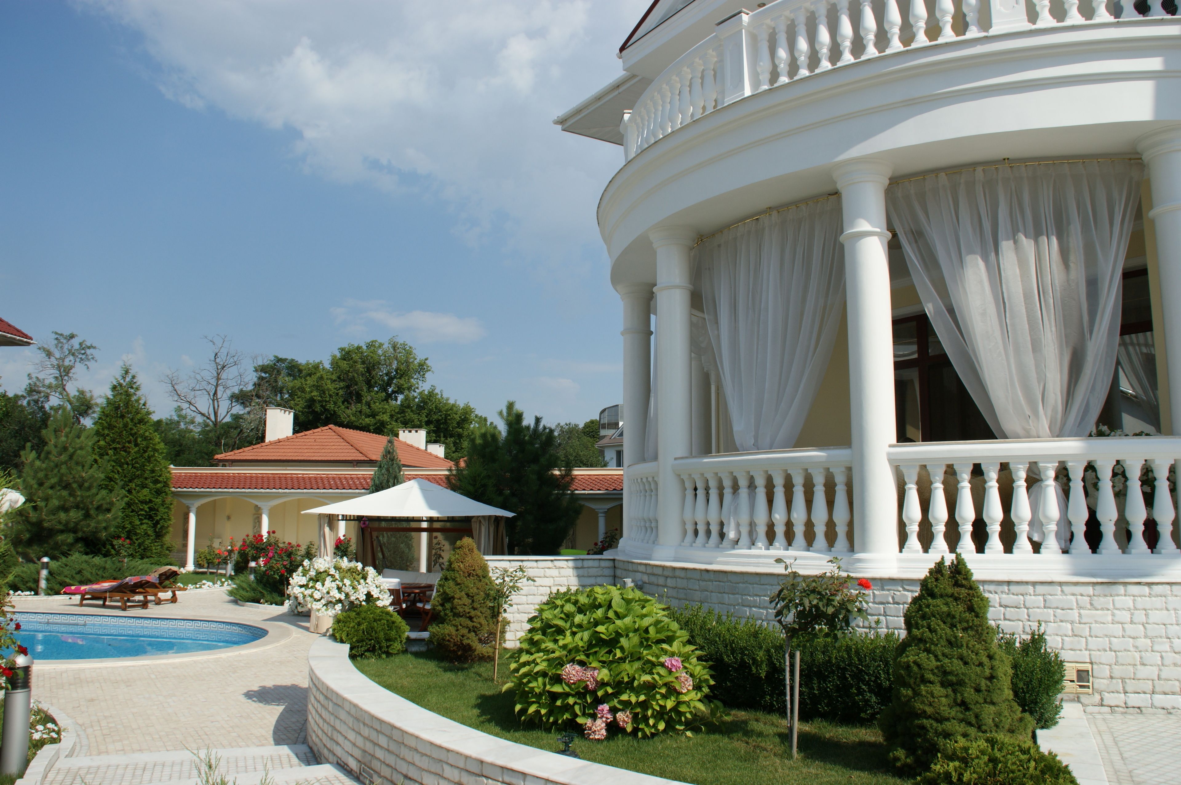 Un bâtiment blanc doté d’un balcon, d’une piscine et d’un jardin.