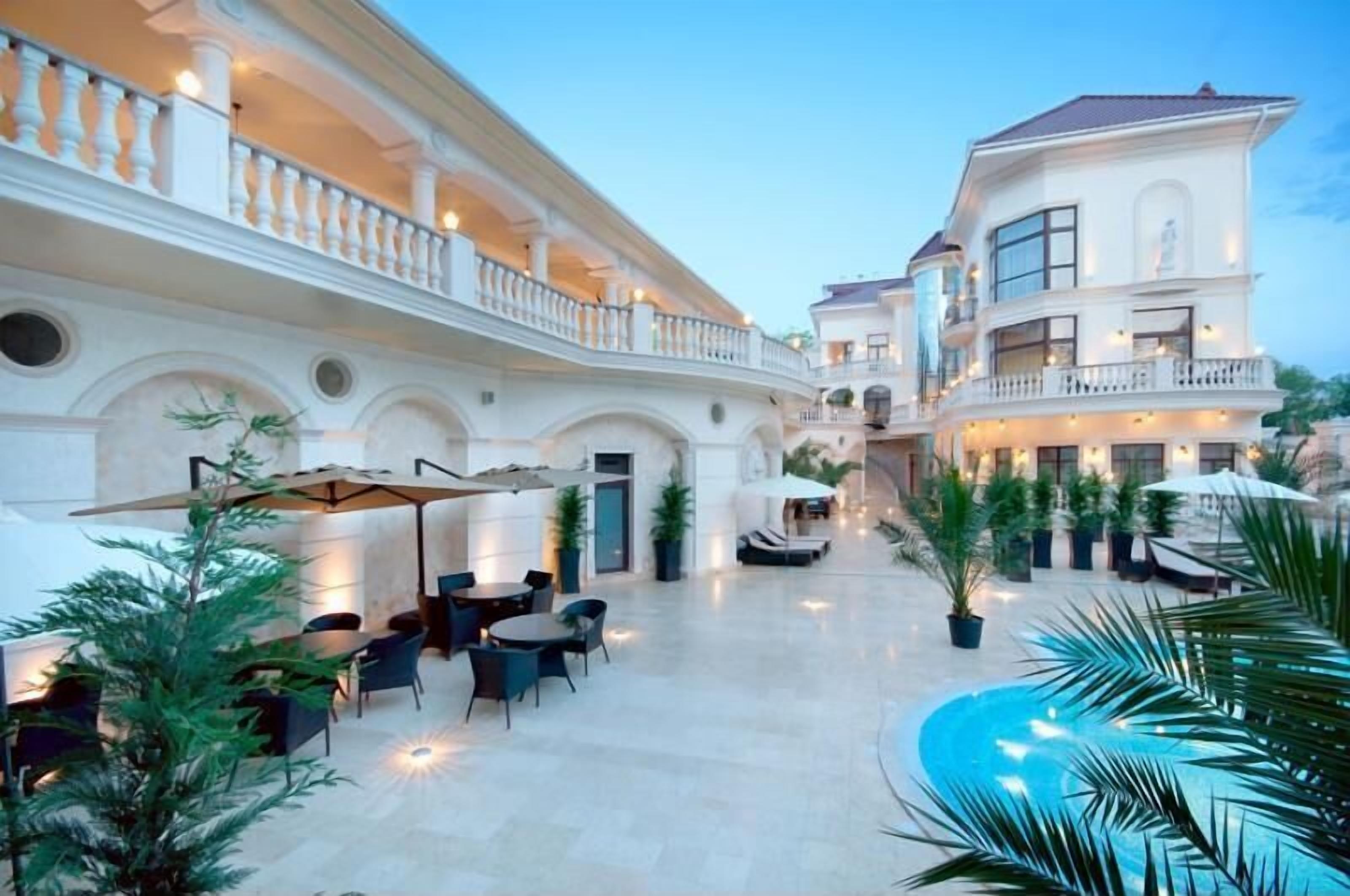 A spacious outdoor area with a pool, multiple dining tables, and umbrellas.