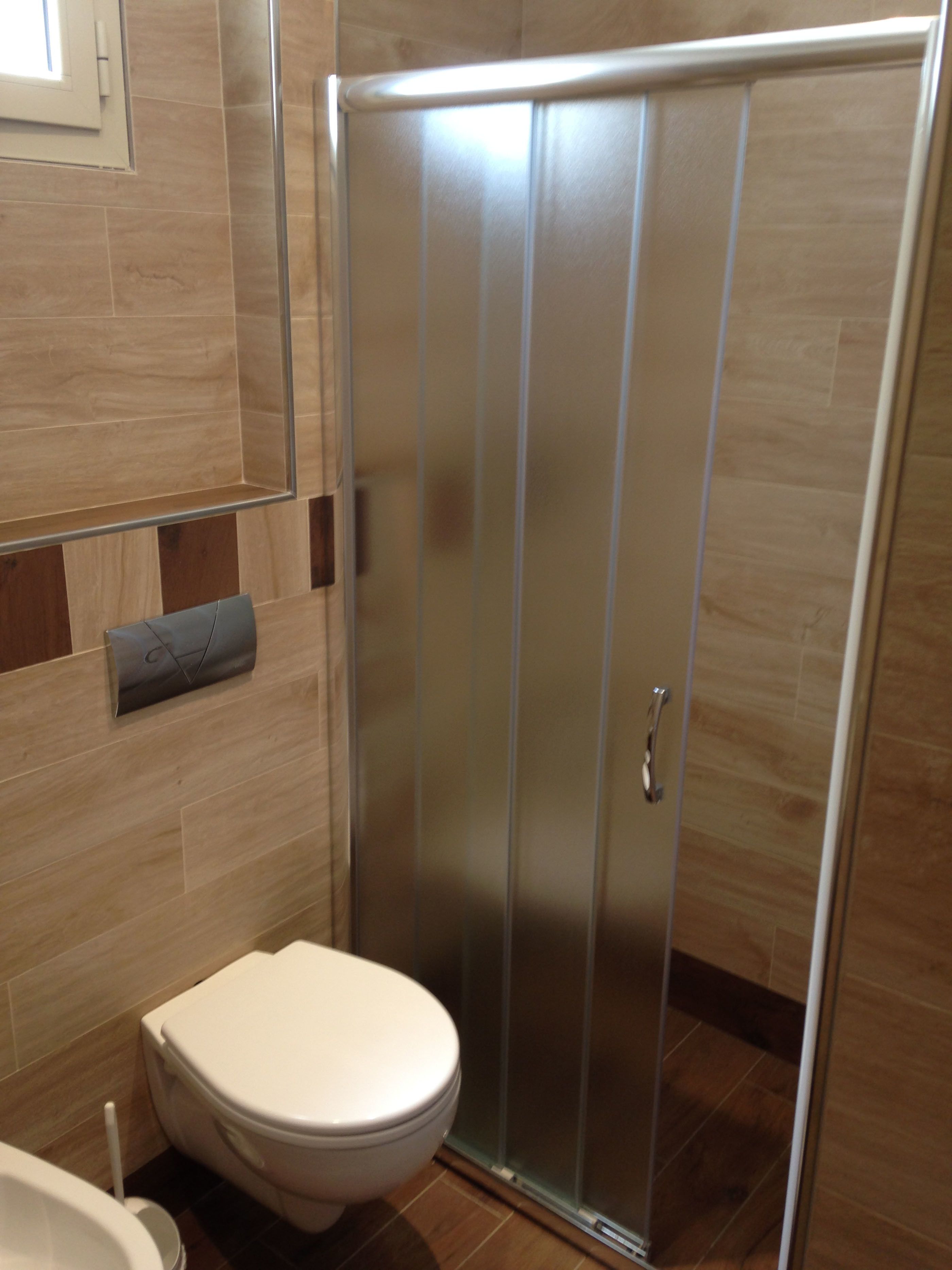 A modern bathroom with a toilet, a shower enclosure, and a towel rack.
