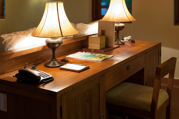 Un bureau en bois avec deux lampes, un téléphone, un bloc-notes et une petite boîte.
