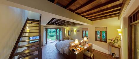 Un dormitorio con cama, mesita de noche, lámpara y vistas al exterior.