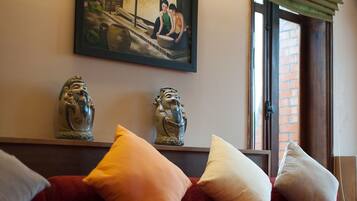 A room with a bed, pillows, a painting, and two decorative figures.