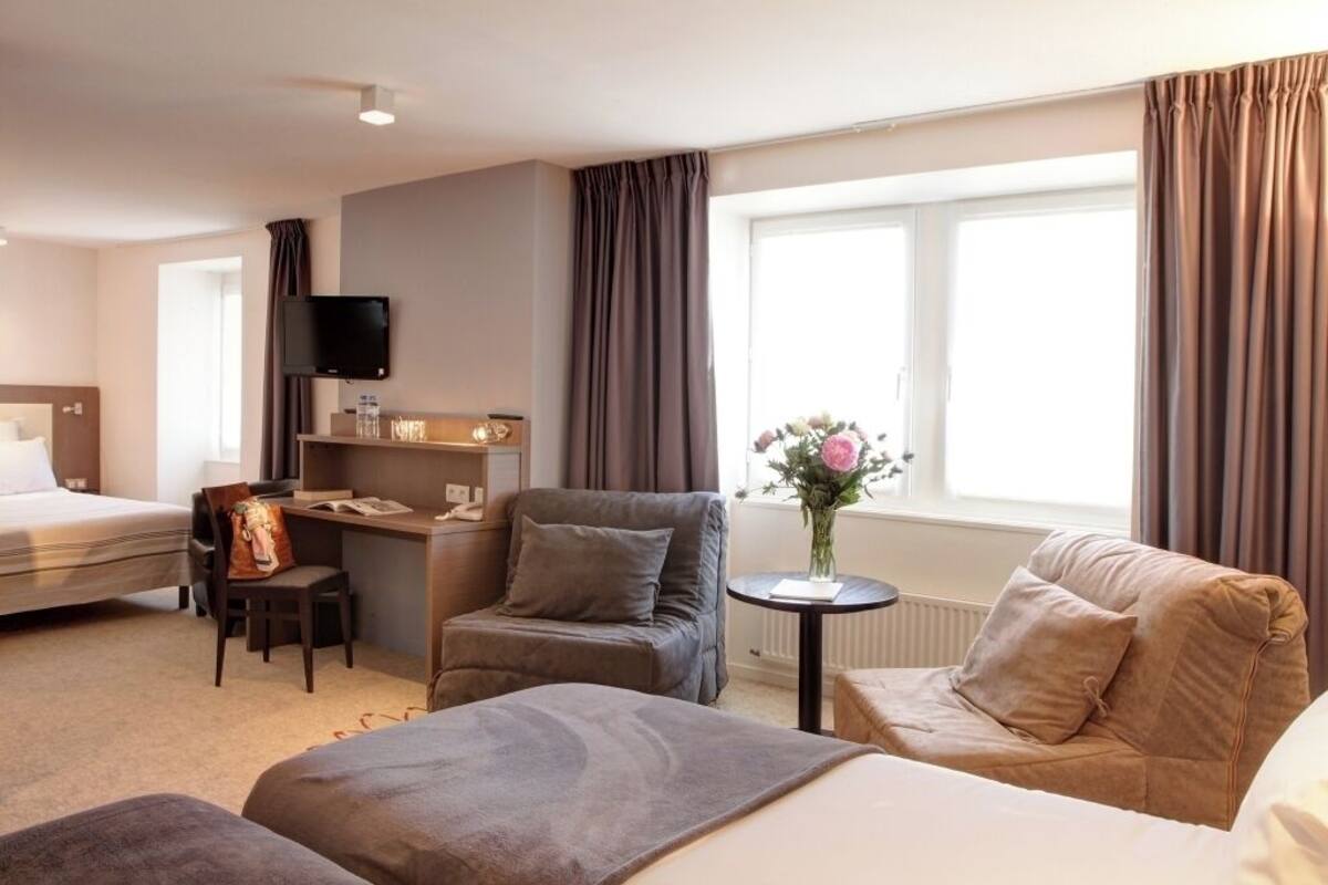 Une chambre d’hôtel avec un lit, un bureau, une chaise et un canapé.
