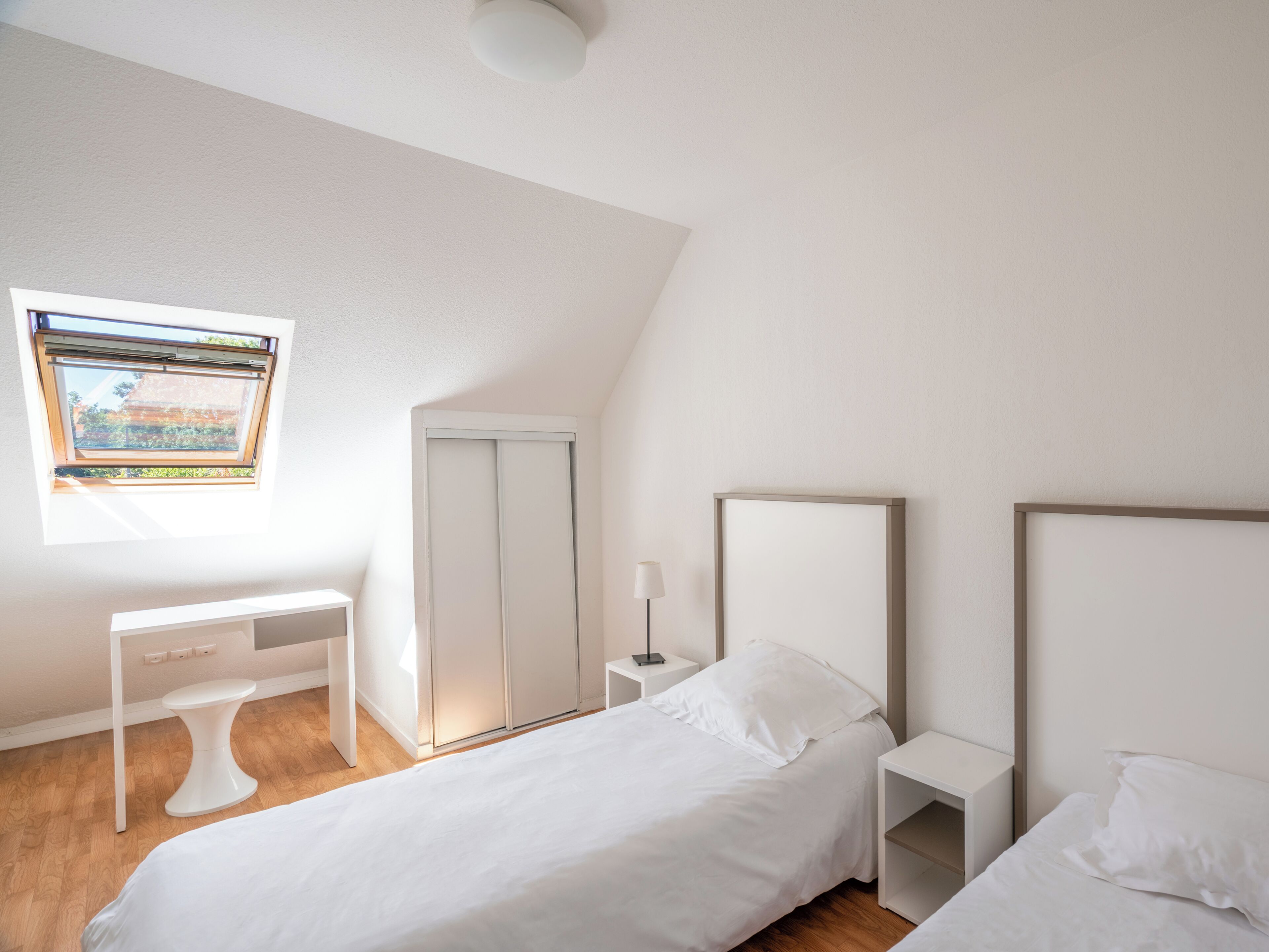 Un dormitorio con cama, escritorio, armario y ventana.