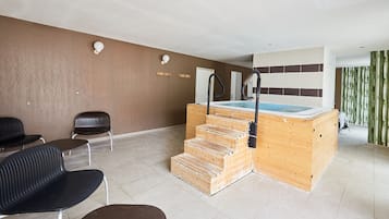 Un espace bien-être comprenant un sauna en bois, des fauteuils noirs et un sol carrelé.