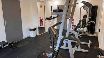 A gym with exercise equipment, a door, and a trash bin.