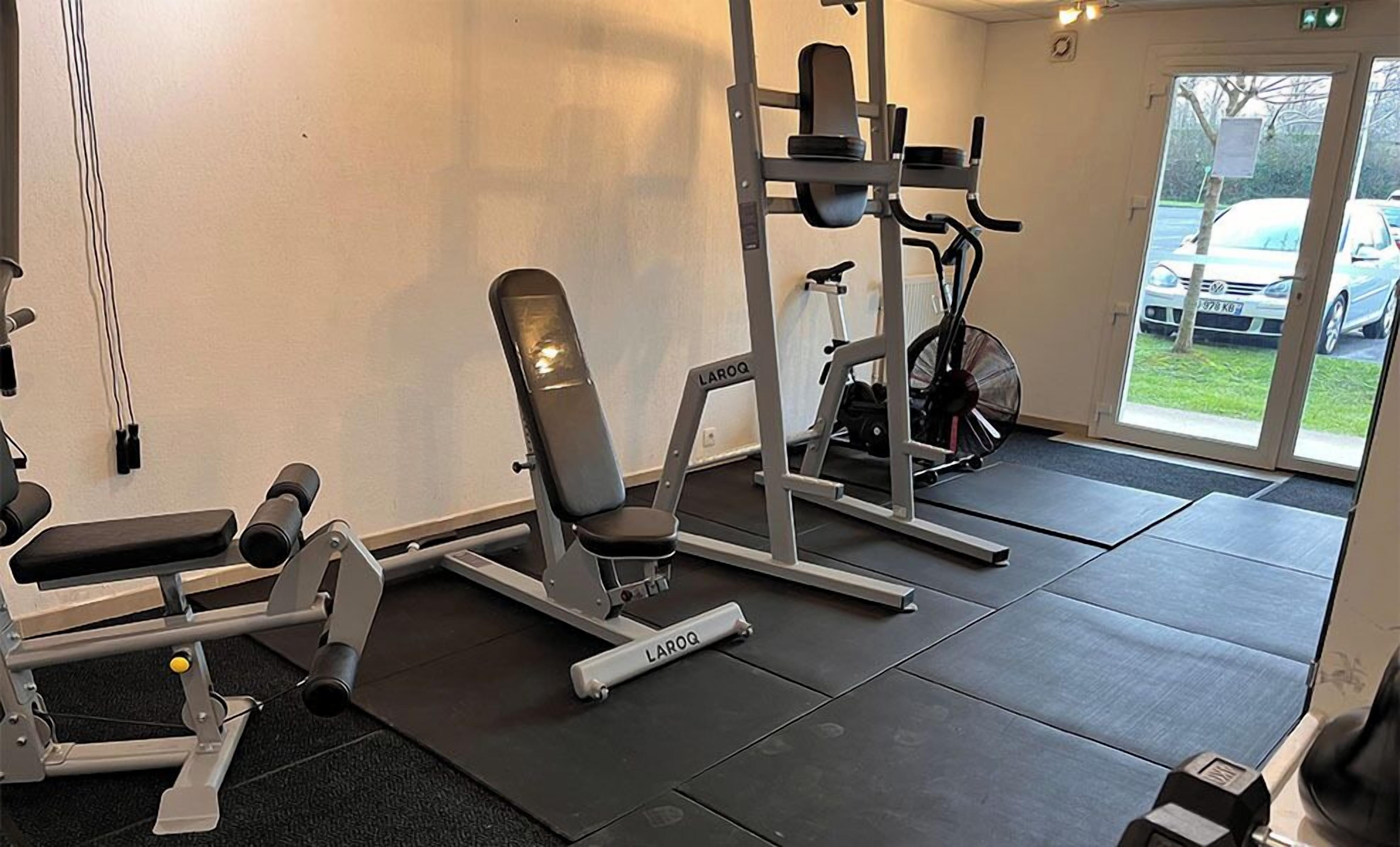 A gym with various exercise equipment including a bench, weight bench, and a multi-functional machine.