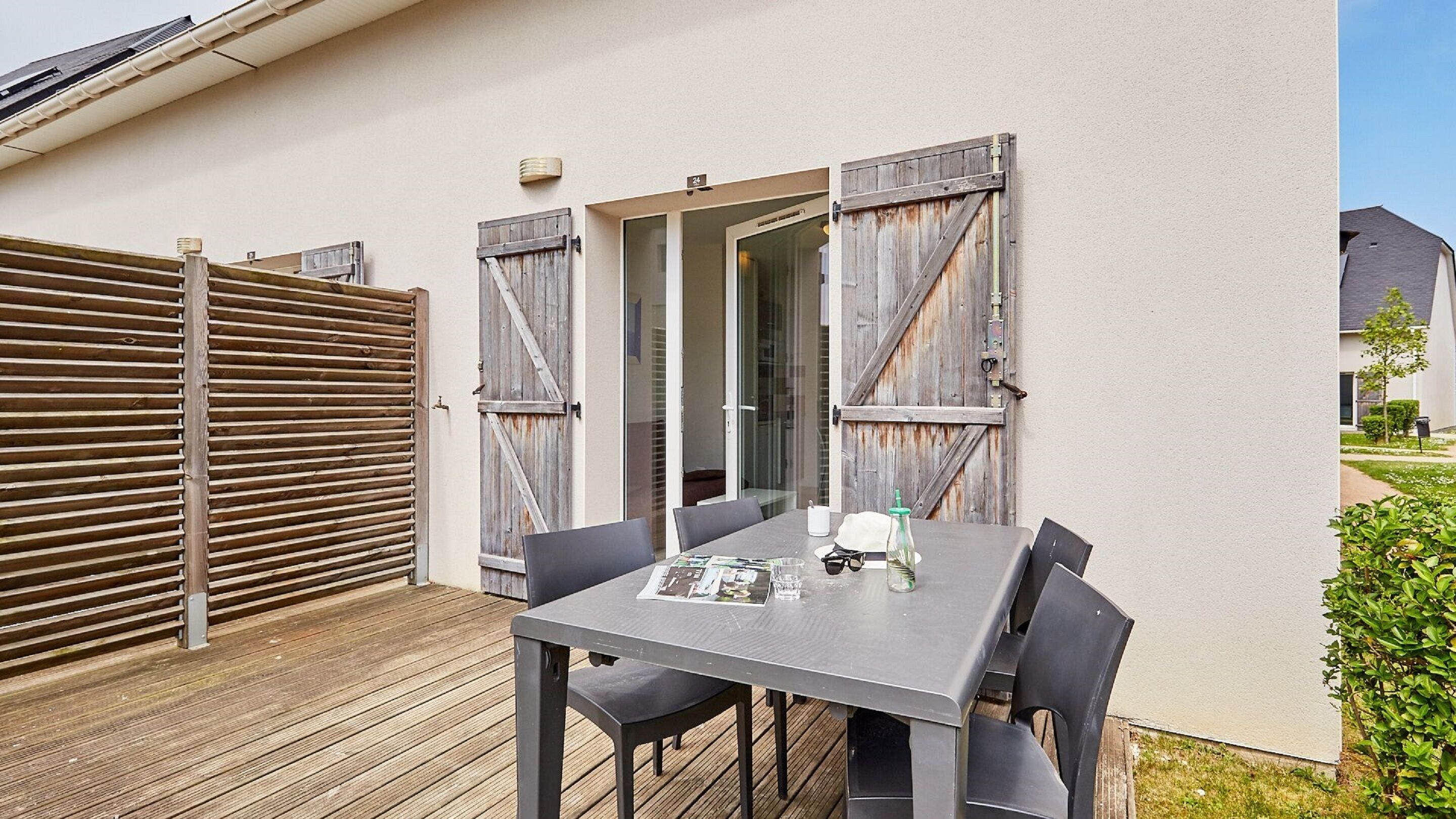 An outdoor patio with a table and chairs, a wooden fence, and a building entrance.