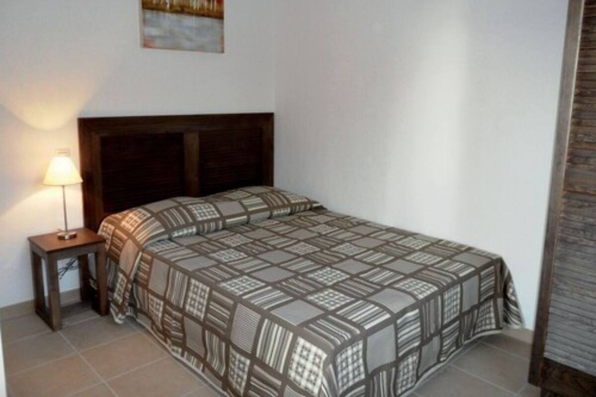 A bedroom with a bed, a nightstand, a lamp, and a painting on the wall.