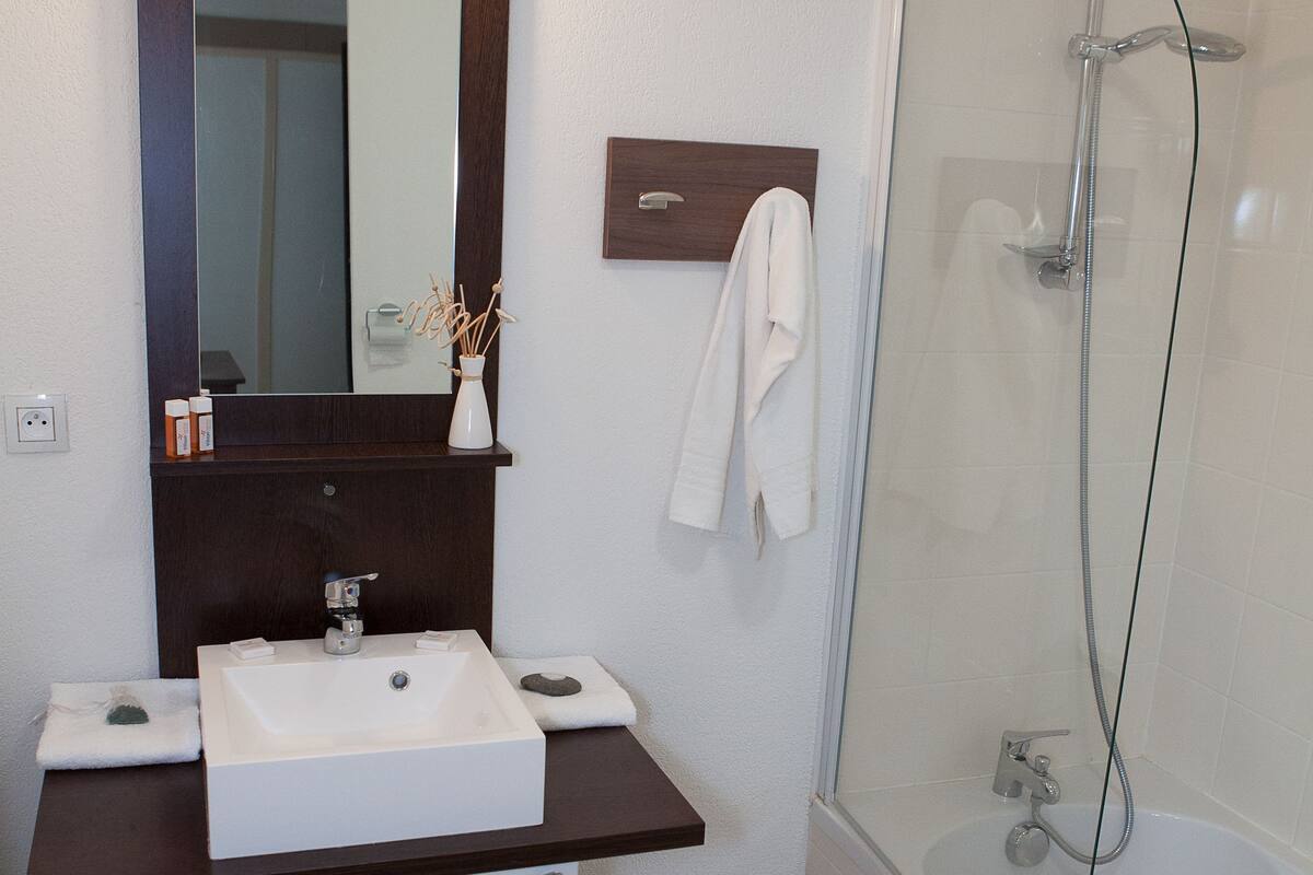 A bathroom with a white sink, mirror, and shower.