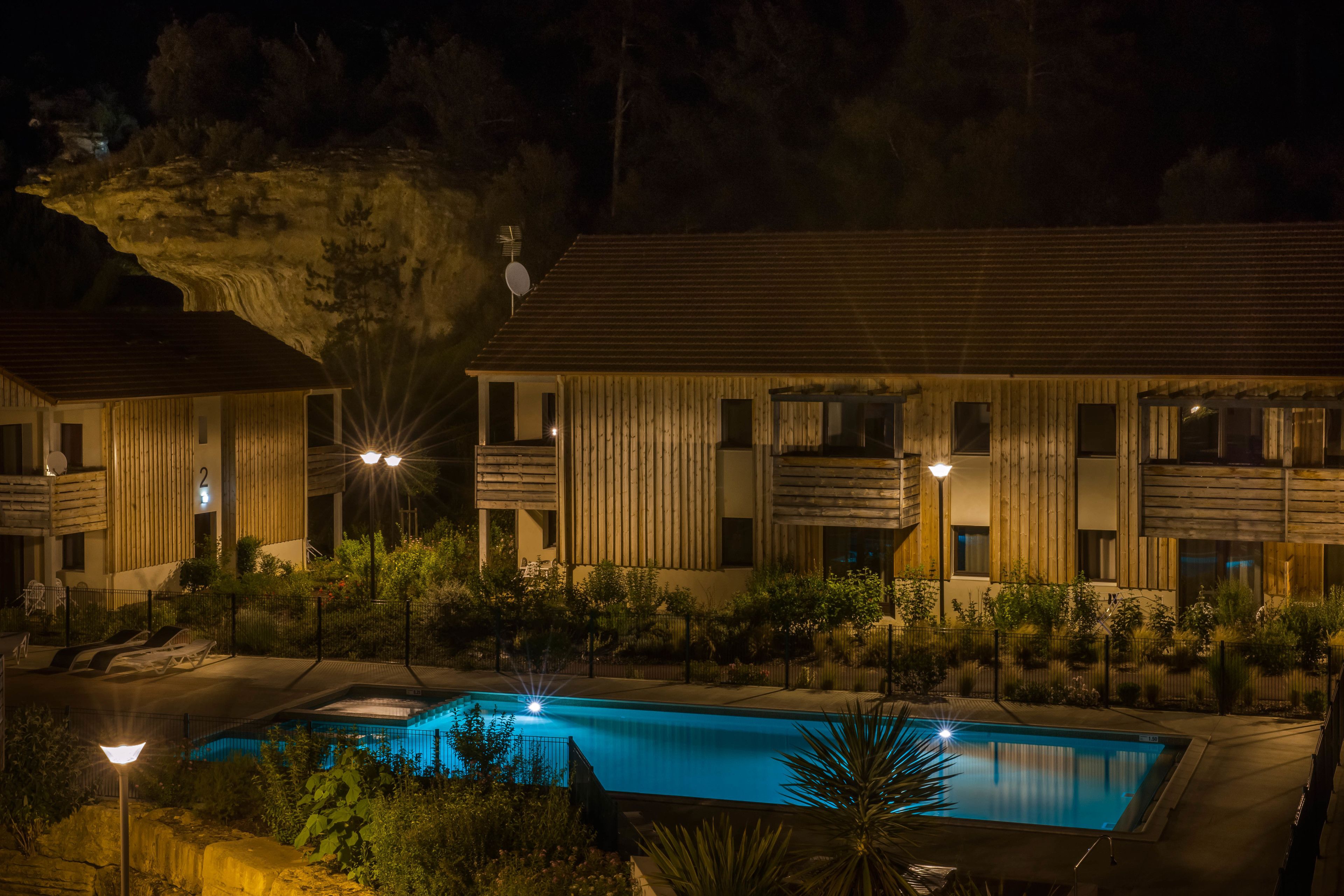 Un hotel moderno con piscina, facciata in legno e numerosi balconi.