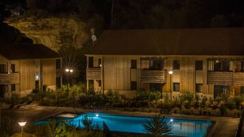 A modern hotel with a swimming pool, wooden exterior, and multiple balconies.