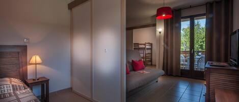 Une chambre d’hôtel avec un lit, un bureau, un canapé, une télévision et un balcon avec vue.