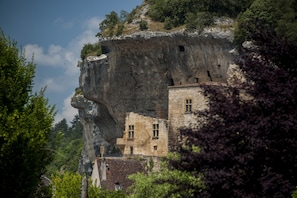 Un edificio histórico de piedra con un escarpado acantilado al fondo, que cuenta con una torre destacada y numerosas ventanas.