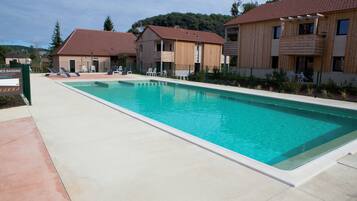 Una piscina rettangolare con bordo piastrellato, circondata da edifici in legno con balconi.