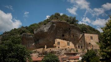 A historic building with stone architecture, situated on a cliff with a view of the surrounding landscape.