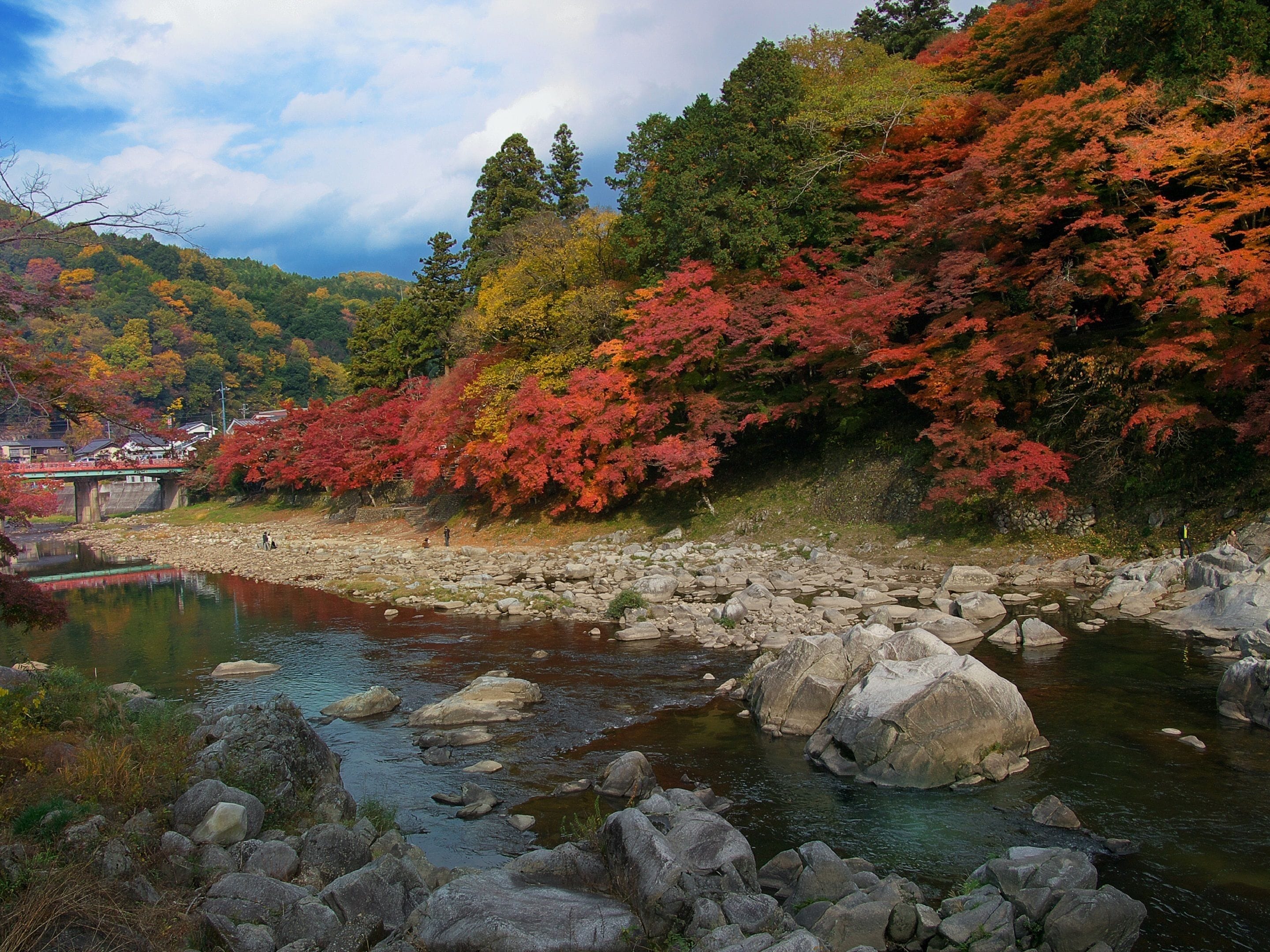 Une rivière bordée de rochers et d’arbres aux feuilles d’automne.