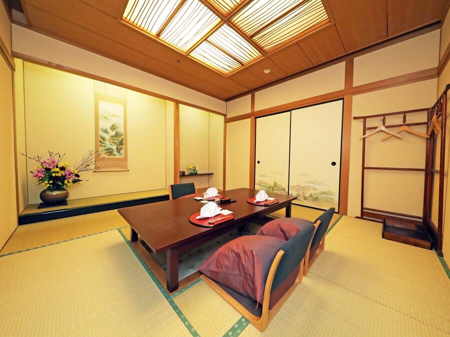 A traditional Japanese room with tatami flooring, a wooden table set for three, and a sliding door.