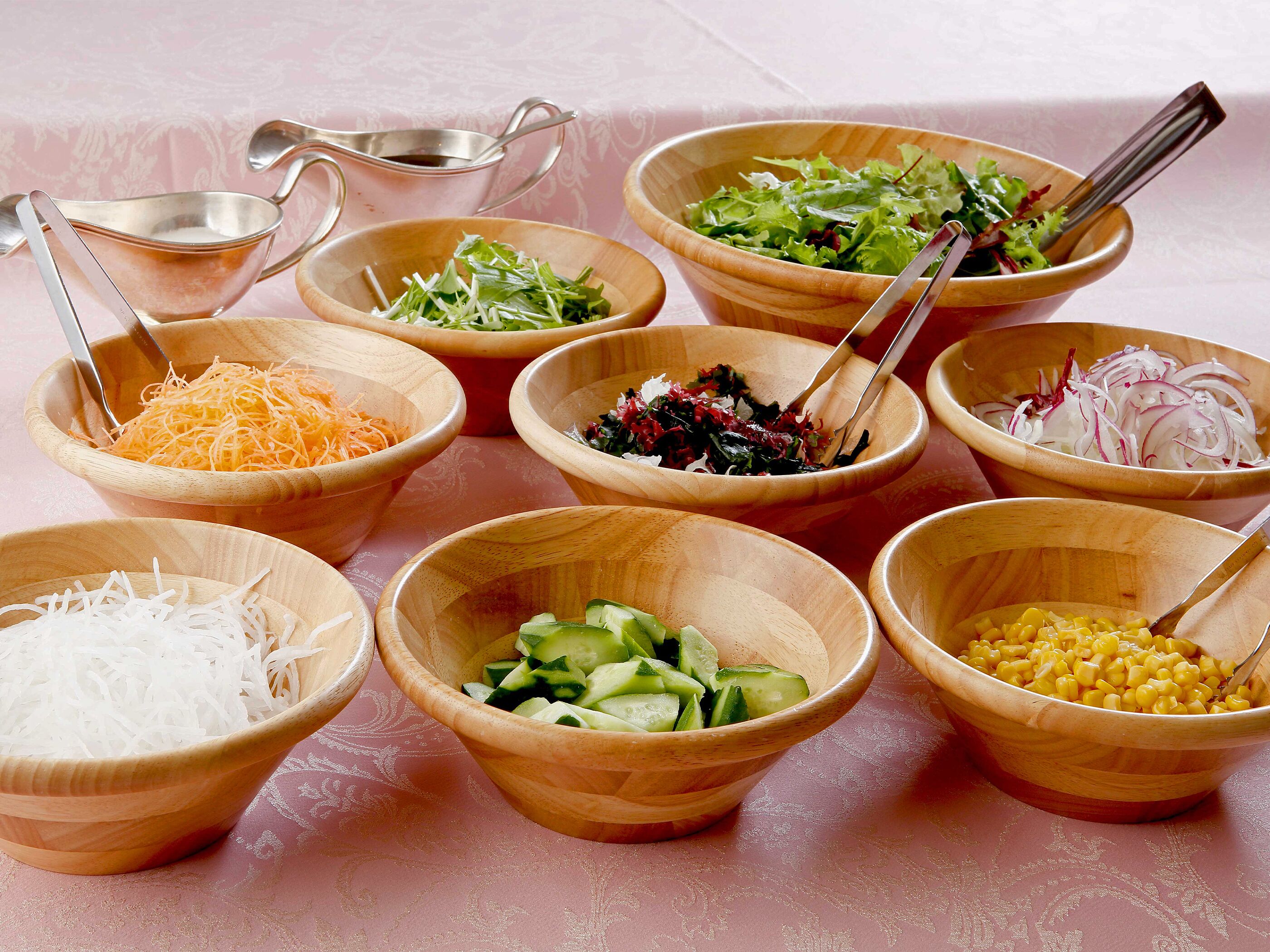 Différents bols en bois contenant divers aliments sont disposés sur une table.