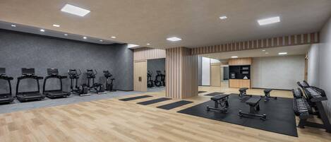 Une salle de sport équipée de tapis de course, de vélos d’exercice et d’appareils de musculation.