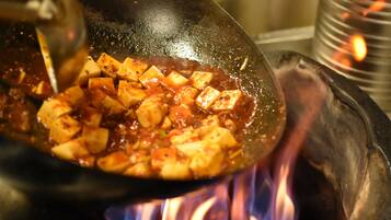 Ein Wok mit Tofu und Sauce wird über offener Flamme gebraten.
