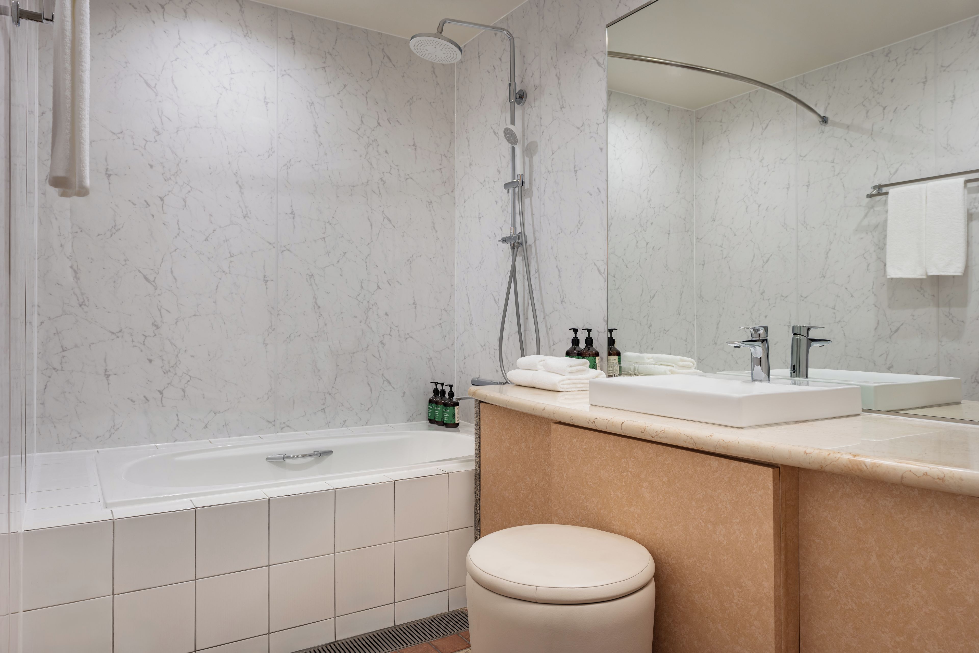 Une salle de bain moderne équipée d’une baignoire, d’une douche, d’un meuble-lavabo et de toilettes.