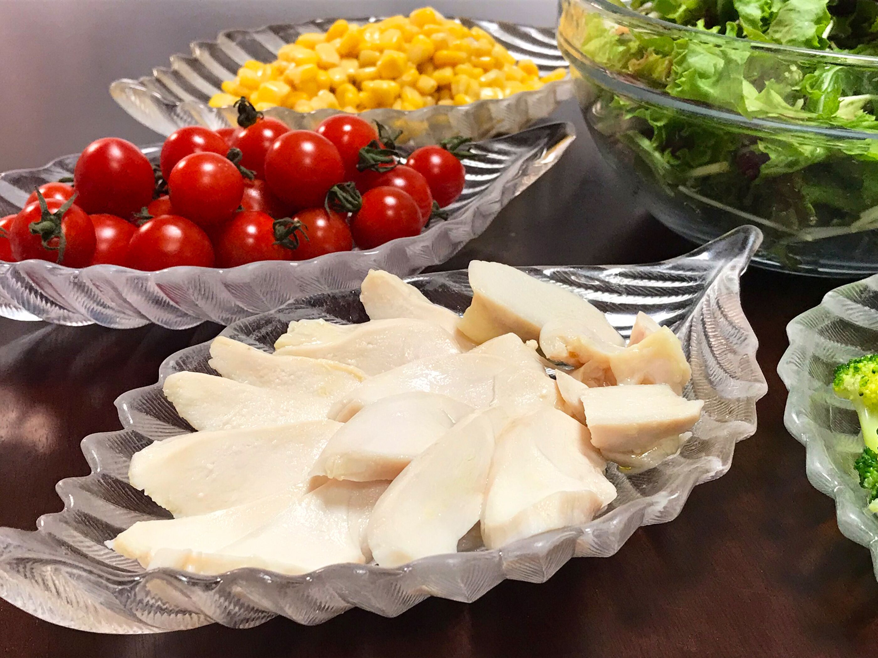 A table with various food items including chicken, tomatoes, corn, and a salad.