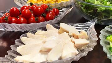 A table with various food items including chicken, tomatoes, corn, and a salad.